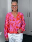 Frau mit Brille, lächelt in bunter Bluse.