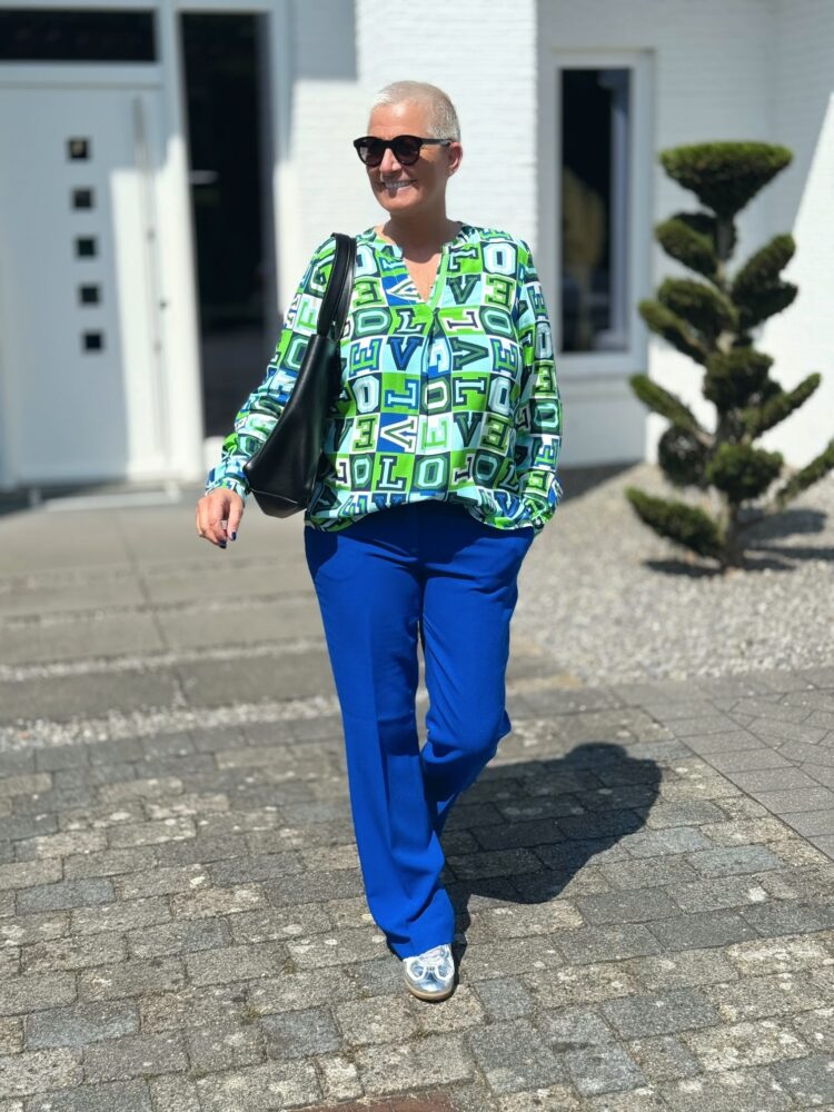 Frau in bunter Bluse spaziert draußen