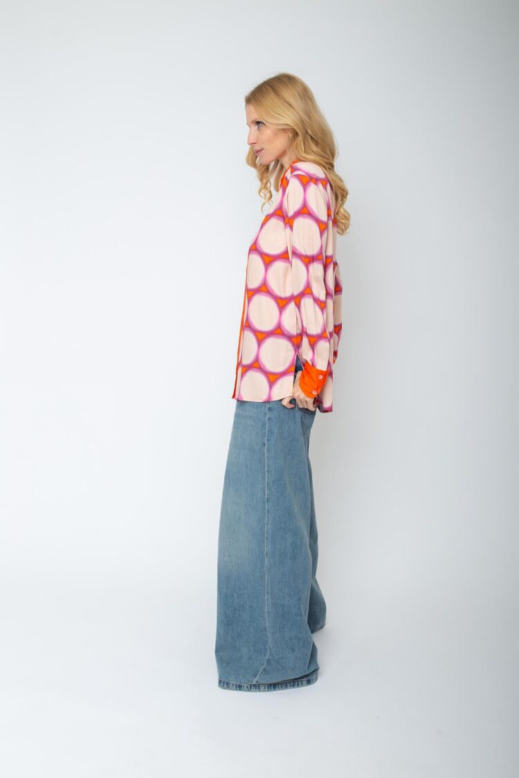 Frau in gemusterter Bluse und Jeanshose