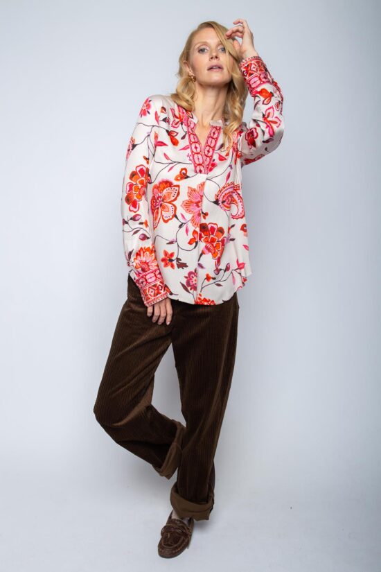 Frau in geblümter Bluse und brauner Hose