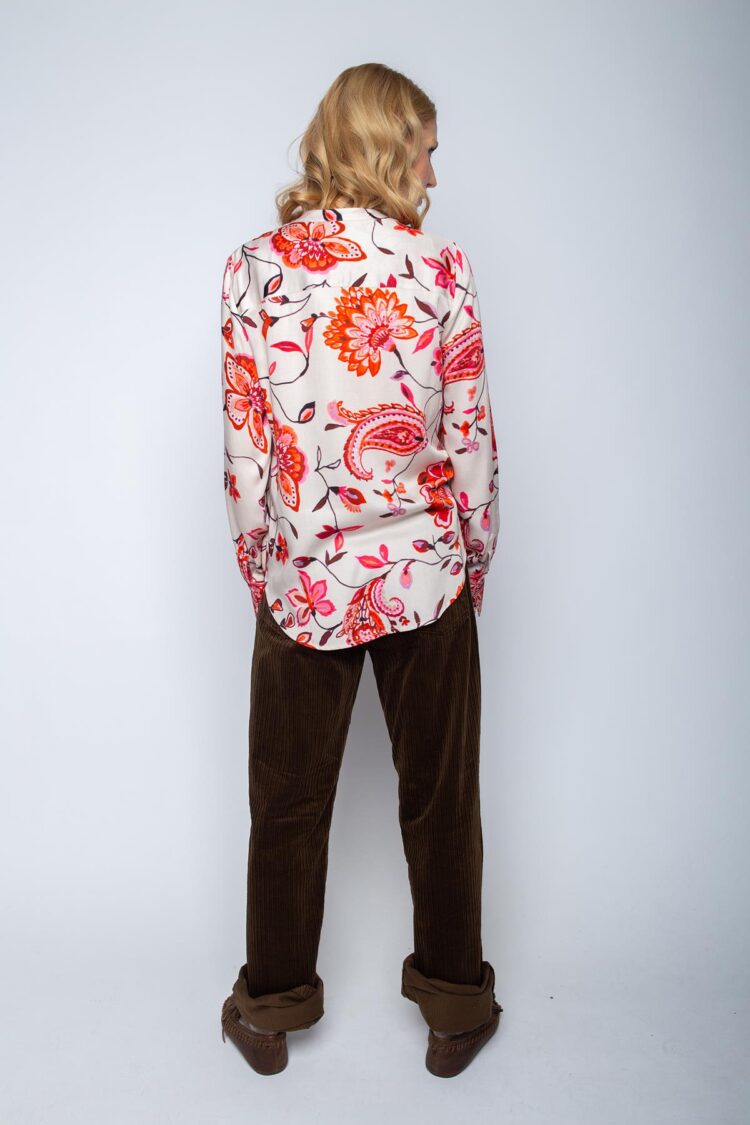 Person von hinten in bunter Bluse und brauner Hose.