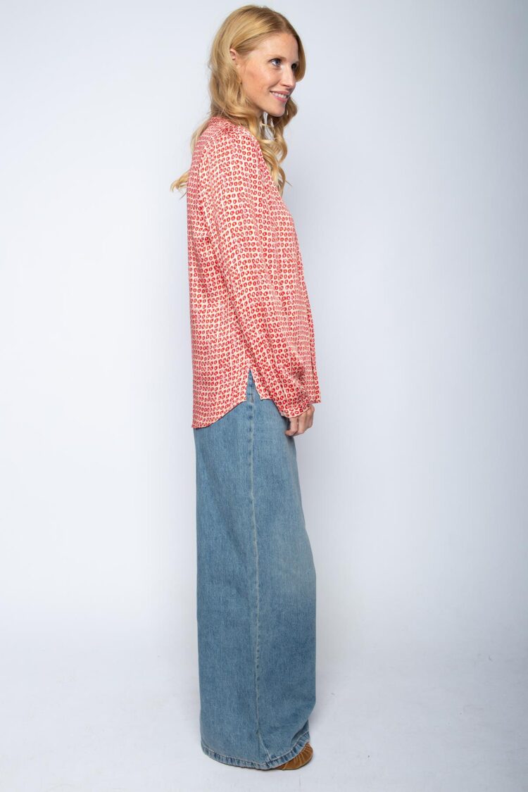 Frau in gemusterter Bluse und Jeansrock, seitlich