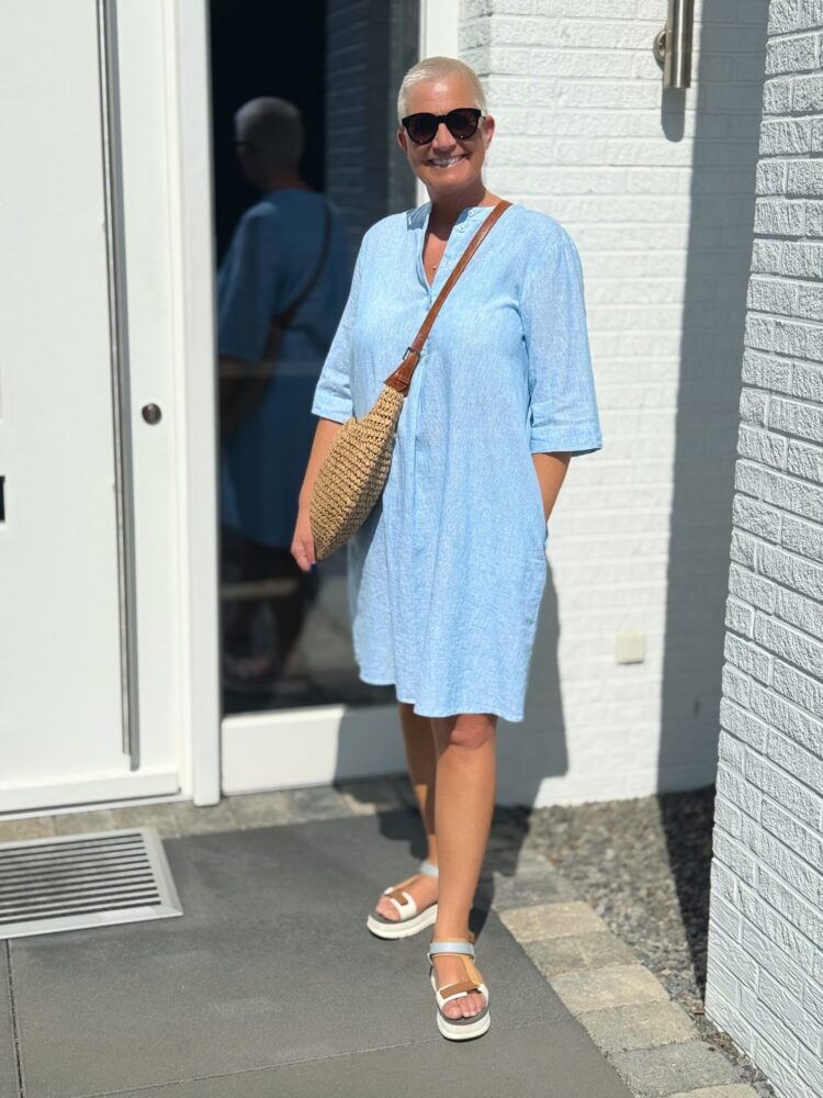 Frau in blauem Kleid vor weißer Tür.