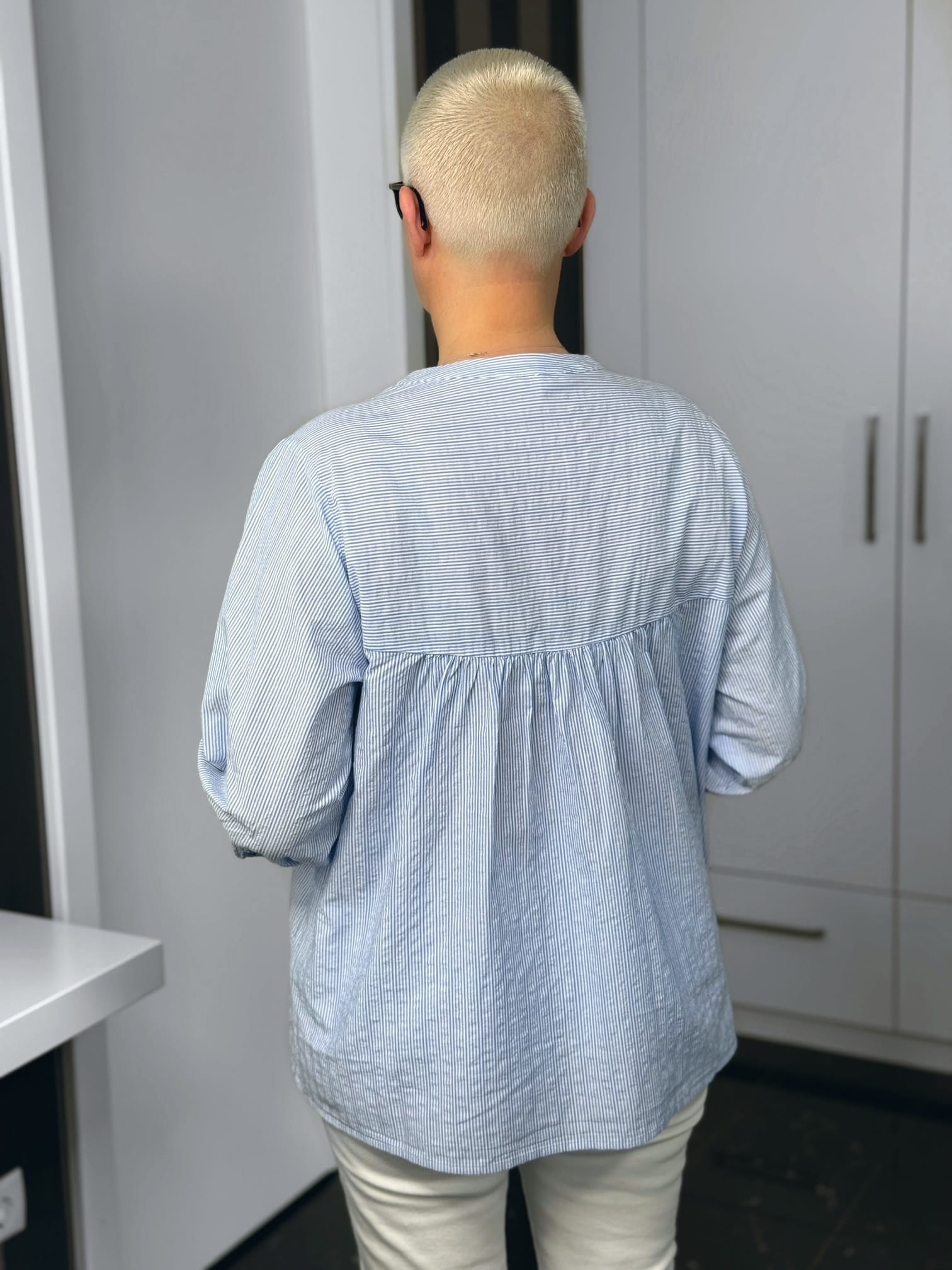 Milano Italy-Bluse-62-2355-5066-1622-7 Person mit blondem Buzzcut von hinten im Raum