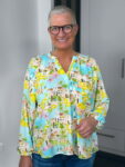 Lächelnde Frau mit bunter Zitronenbluse und Brille