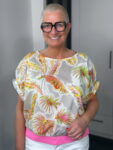 Lächelnde Frau mit Kurzhaarschnitt und Blumenbluse