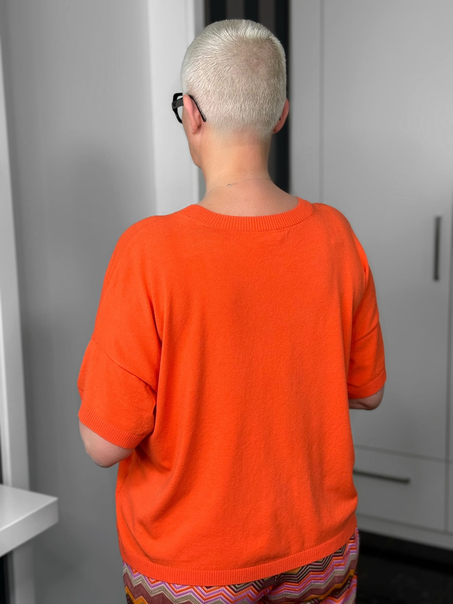 Milano Italy-Pulli-62-5268-9046-300-6 Person mit kurzem blondem Haar und orangem Pullover
