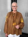 Lächelnde Person mit Brille und brauner Bluse