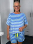 Lächelnde Frau mit Brille im blau gestreiften Outfit