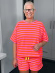 Lächelnde Frau in pink-orange gestreiftem Outfit