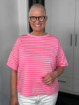 Lächelnde Person mit Brille und pinkem Streifenshirt