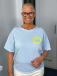 Lächelnde Person mit Brille und Smiley-Shirt