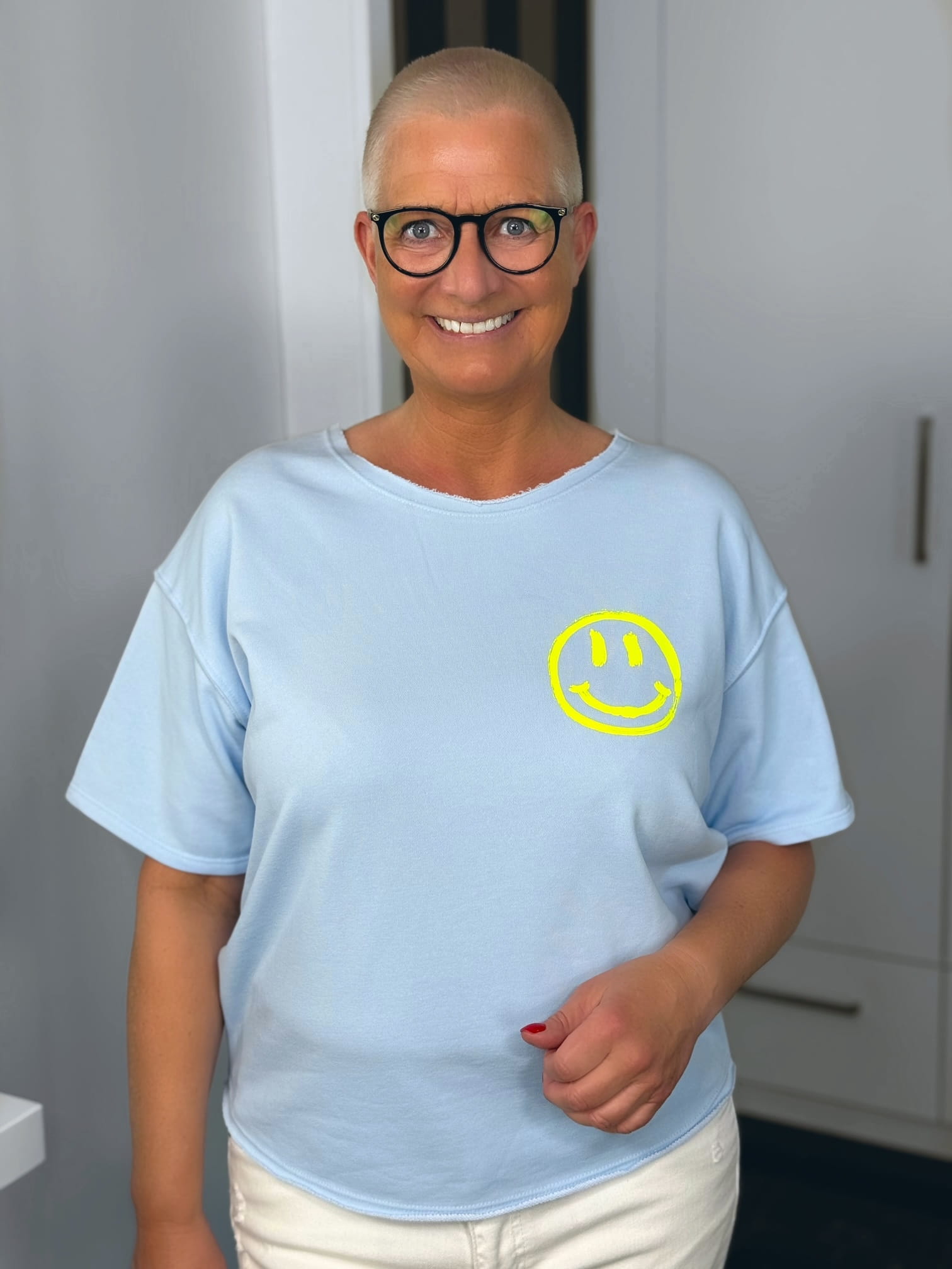 markenfest-Shirt-H1140-blau-1 Lächelnde Person mit Brille und Smiley-Shirt
