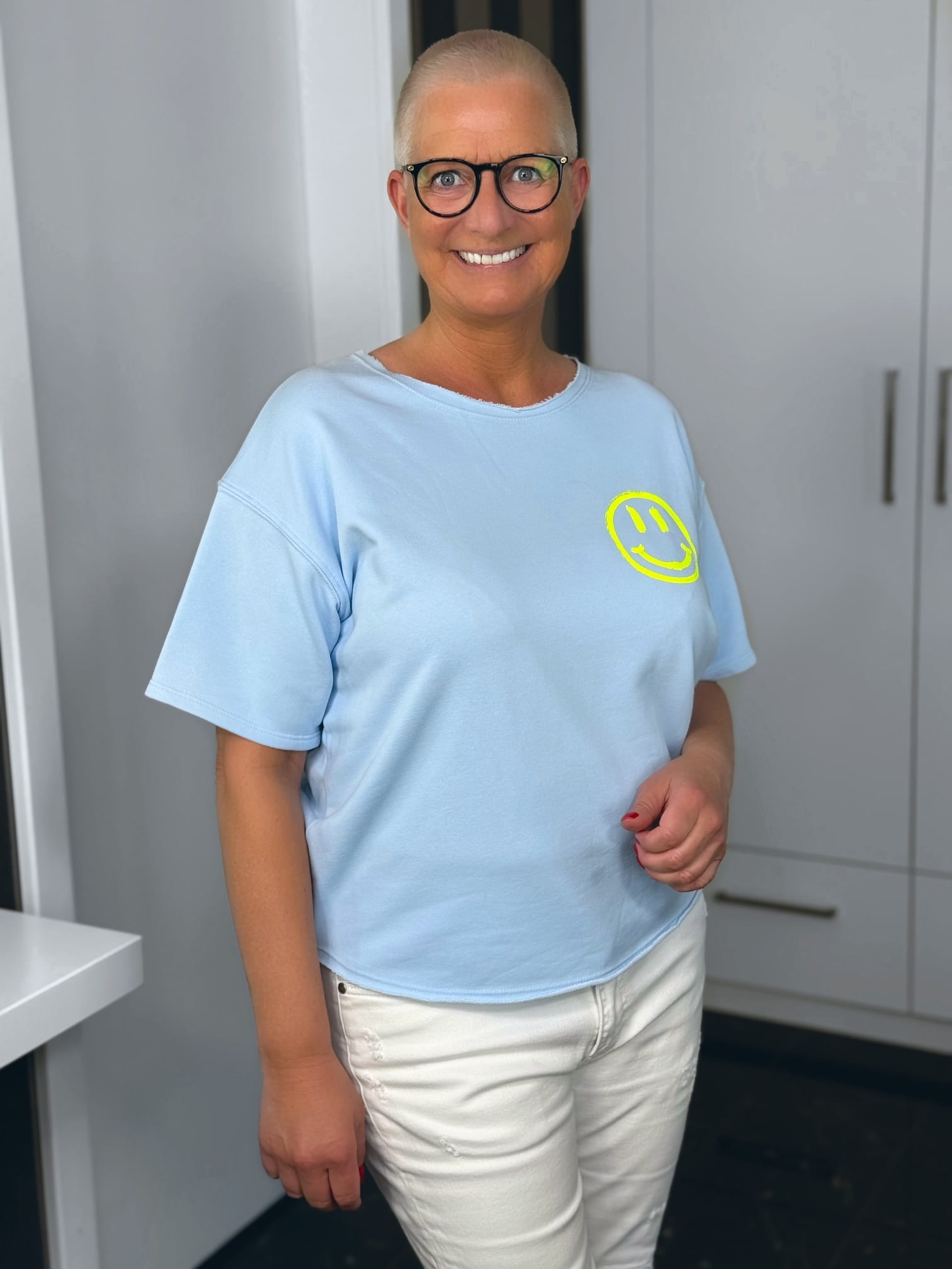 markenfest-Shirt-H1140-blau-2 Lächelnde Person mit Brille und Smiley-Shirt
