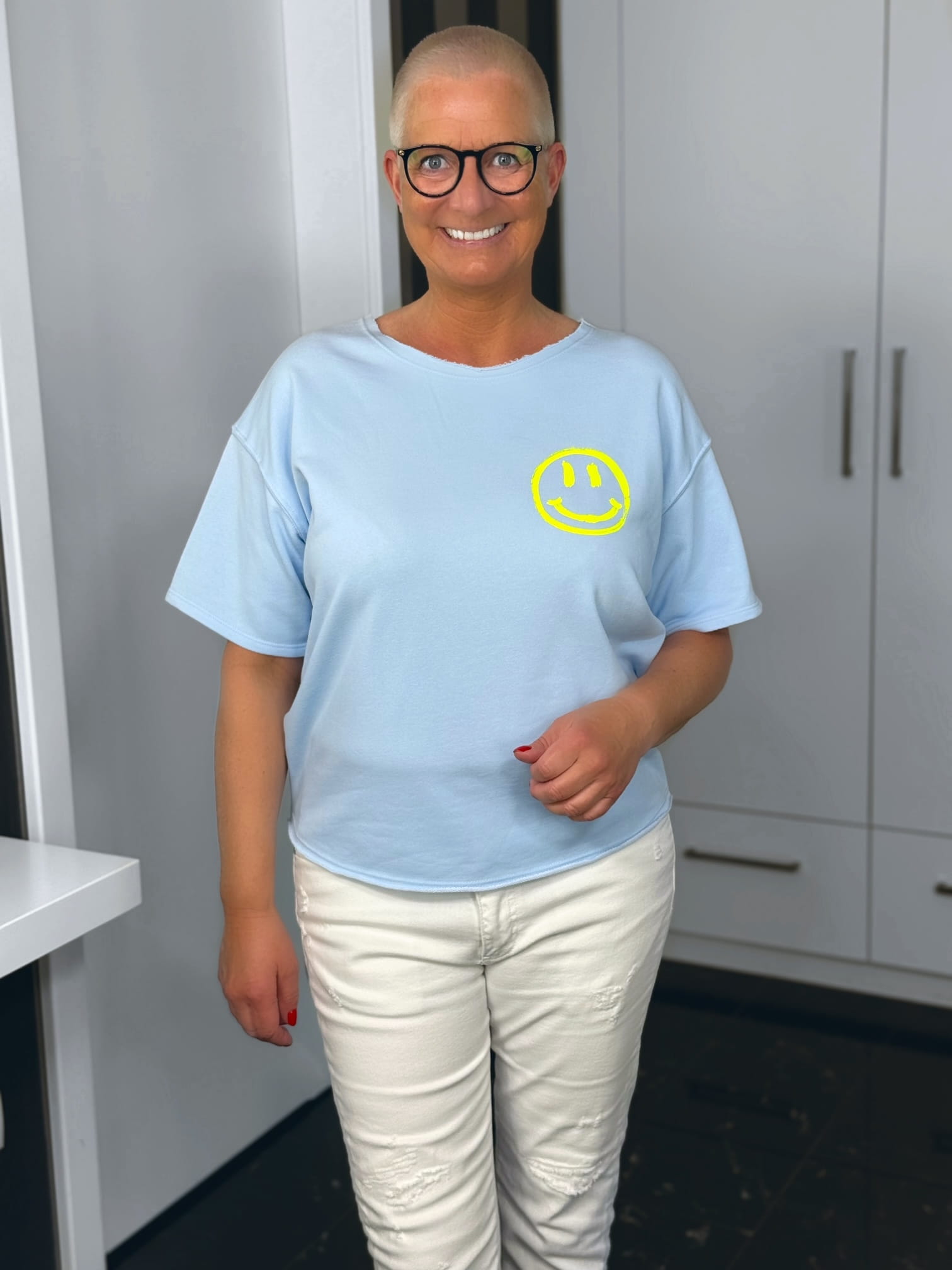 markenfest-Shirt-H1140-blau-3 Lächelnde Frau mit Smiley-Shirt und Brille