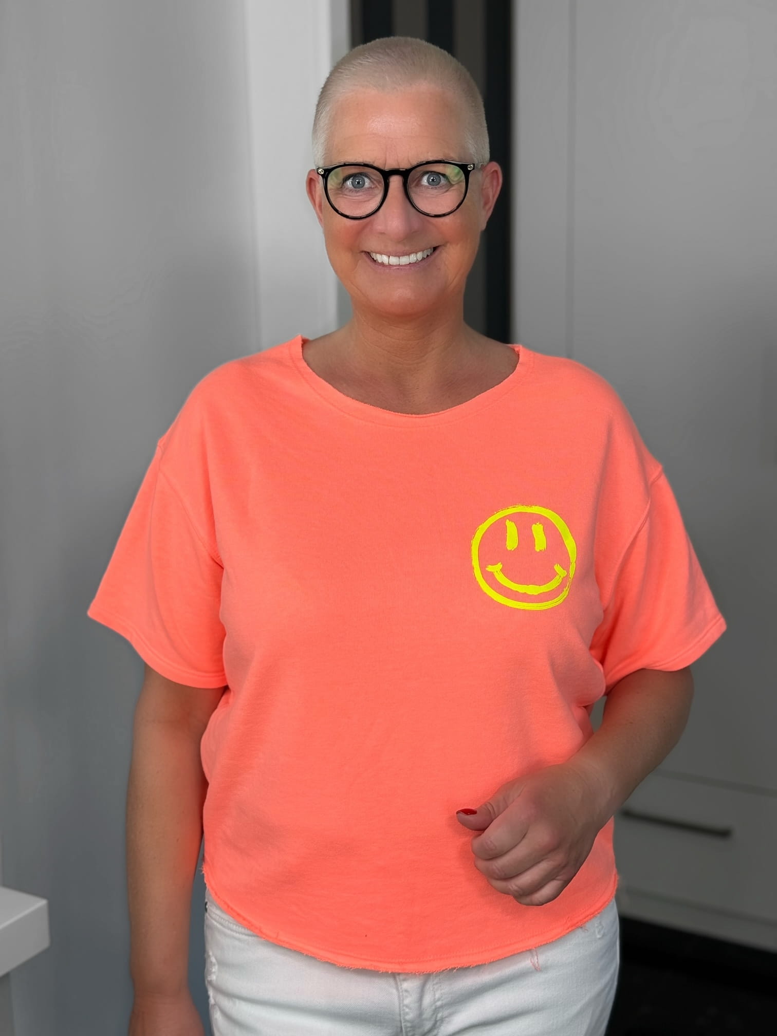 markenfest-Shirt-H1140-orange-1 Lächelnde Person mit Brille und Smiley-Shirt