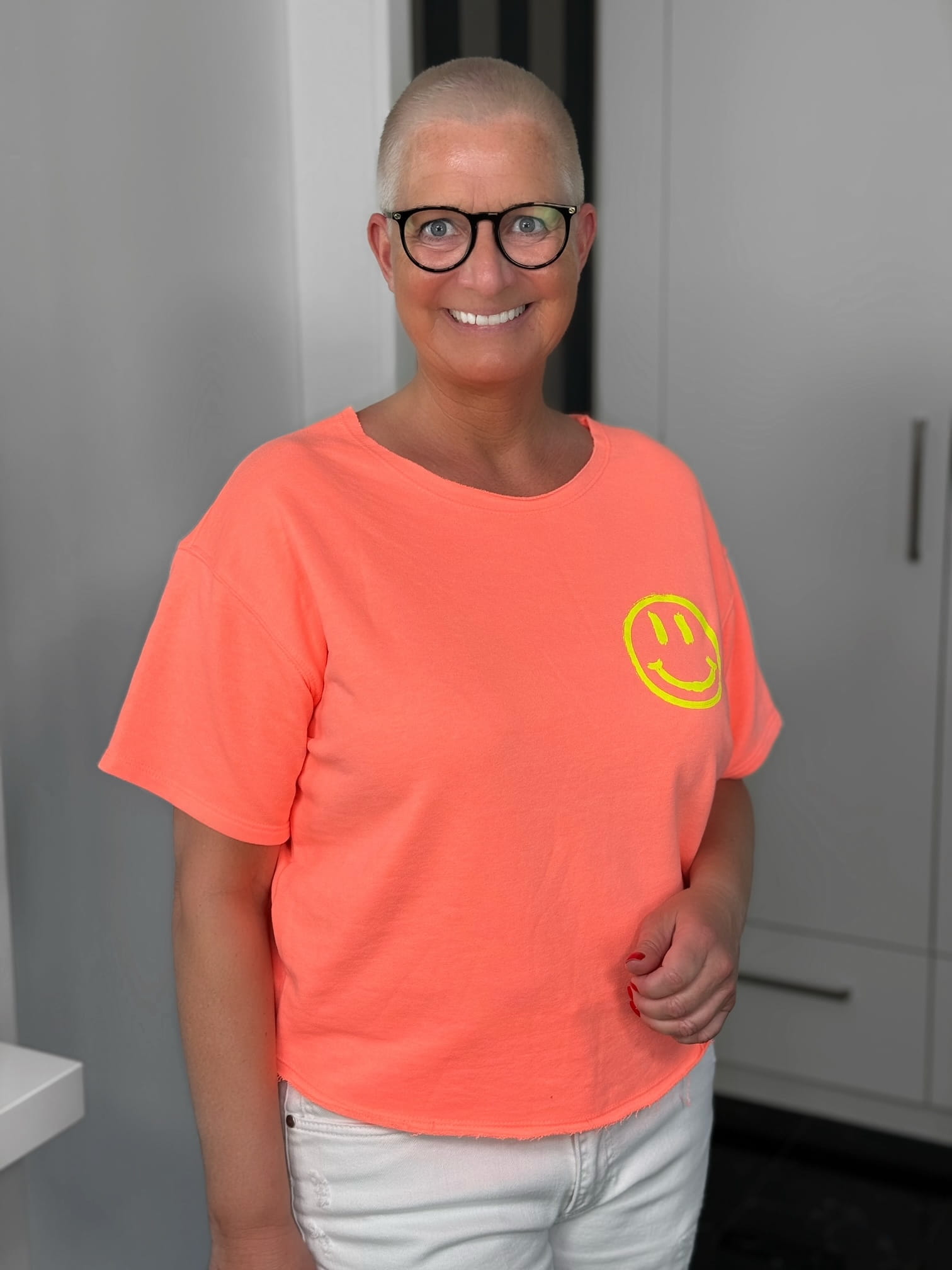 markenfest-Shirt-H1140-orange-2 Lächelnde Person mit Brille und orangem Shirt
