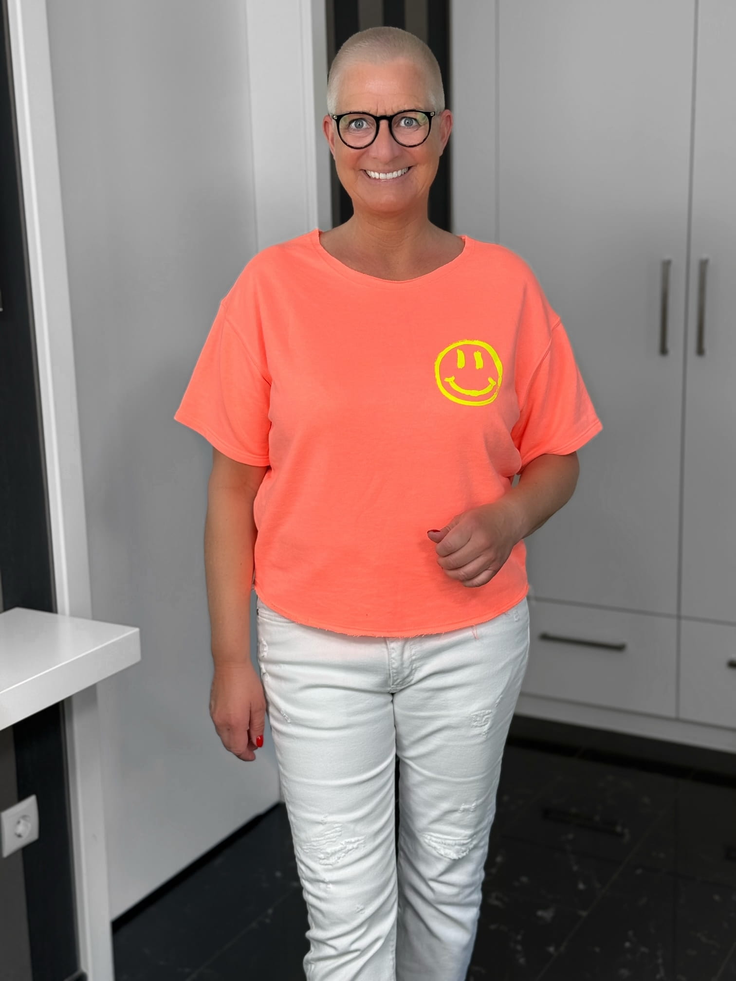 markenfest-Shirt-H1140-orange-3 Lächelnde Frau mit neonorangem Smiley-T-Shirt