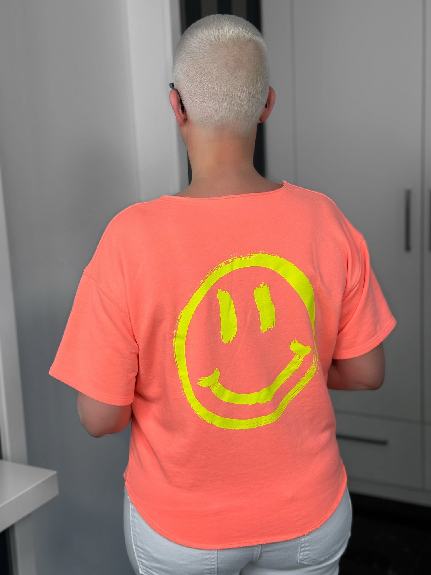markenfest-Shirt-H1140-orange-6 Person mit kurzem blonden Haar und Smiley-Shirt