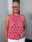 Lächelnde Frau mit Brille und buntem Top
