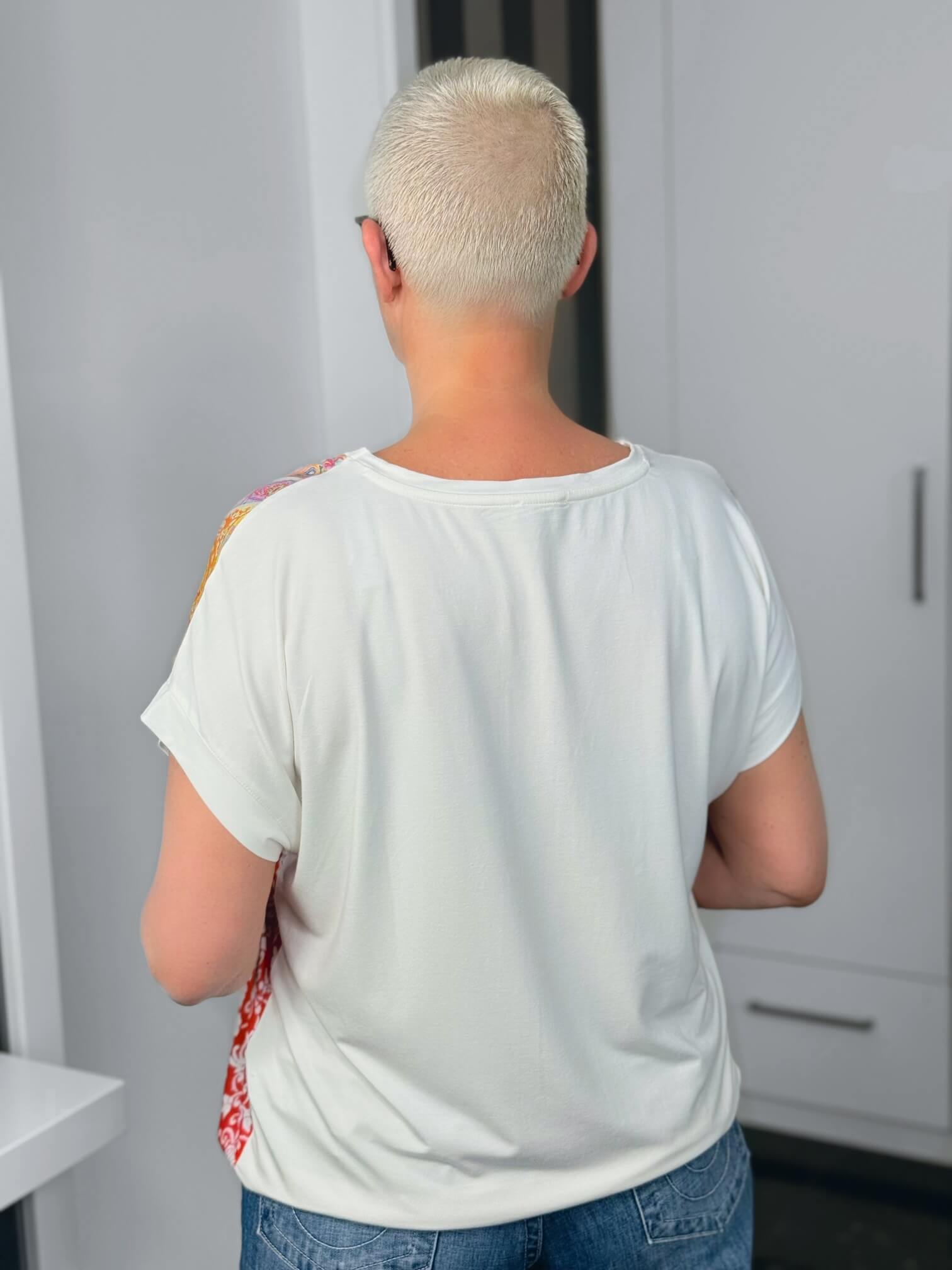 Milano Italy-Bluse-63-5406-8671-104-6 Person mit sehr kurzen platinblonden Haaren von hinten