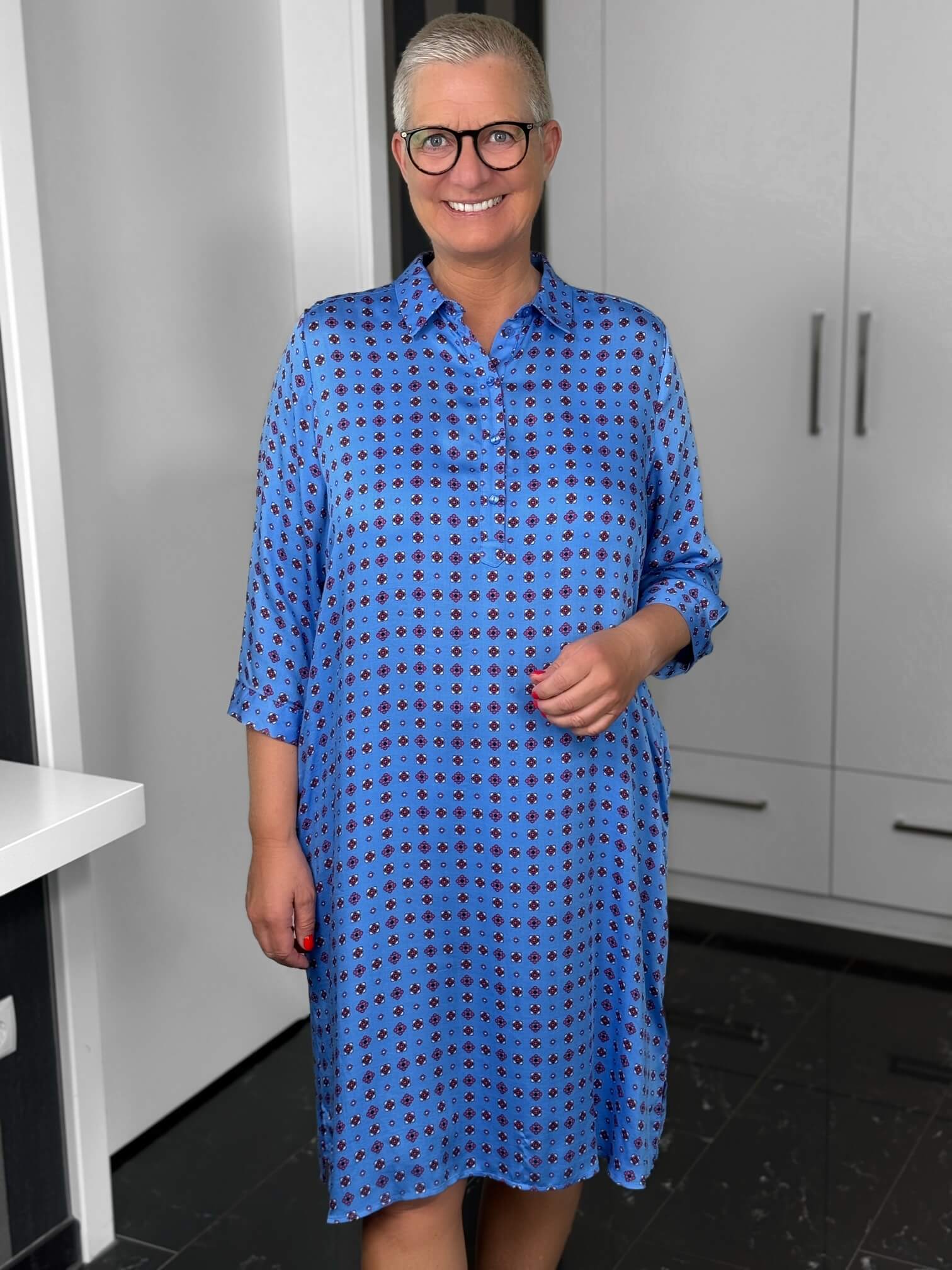 Milano Italy-Kleid-63-6574-5046-1600-3 Lächelnde Frau mit Brille in blauem Kleid